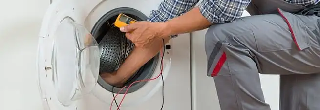 Dryer repair technician inspecting and repairing a clothes dryer in Fresno, CA