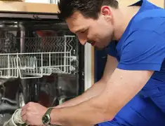 Dishwasher repair technician inspecting and servicing an open dishwasher in Fresno, CA