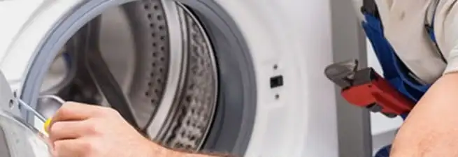 Appliance technician repairing a clothes dryer drum and internal parts in Fresno, CA