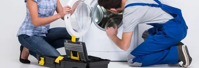 Washer repair technician inspecting a front-load washing machine with tools in Fresno, CA