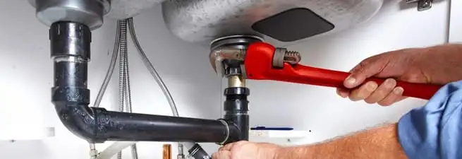 Garbage disposal repair technician tightening the sink drain and disposal connection in Fresno, CA