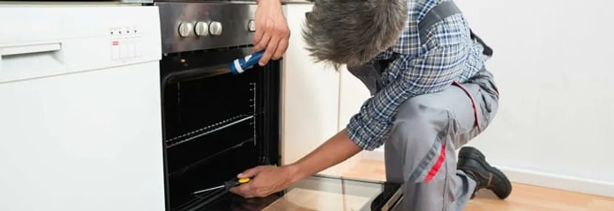 Oven repair technician inspecting and servicing an electric oven in Fresno, CA