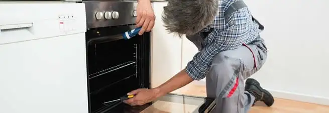 Oven repair technician inspecting and servicing an electric oven in Fresno, CA