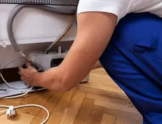 Appliance repair technician fixing refrigerator water line and connections in Fresno, CA