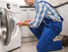 Washing machine repair technician servicing a front-load washer in Fresno, CA