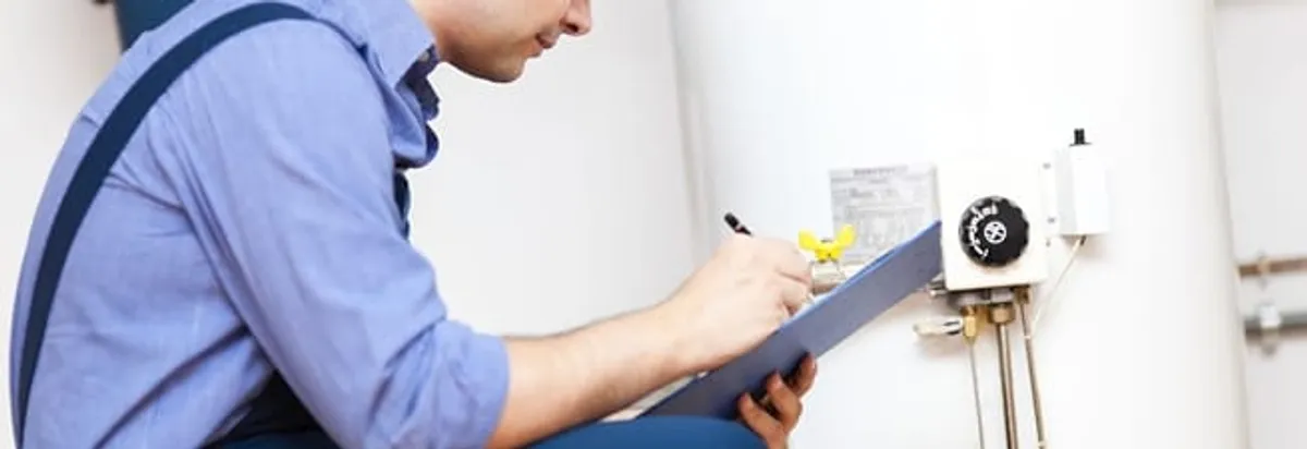 Water heater repair technician inspecting the unit and recording service notes in Fresno, CA