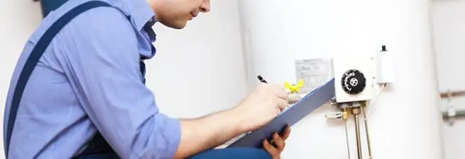 Water heater repair technician inspecting the unit and recording service notes in Fresno, CA
