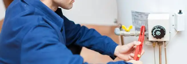 Water heater repair technician adjusting the temperature control and gas valve in Fresno, CA